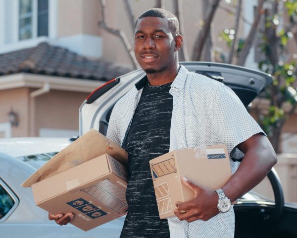 A courier in a residential area delivering packages from a car trunk, representing efficient delivery service.