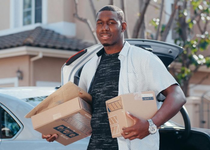 A courier in a residential area delivering packages from a car trunk, representing efficient delivery service.